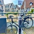 Radstation Gemeinde Steinhagen Fahrradstation mit aufgeladenem E-Bike in urbaner Umgebung, umgeben von modernen und traditionellen Gebäuden.
