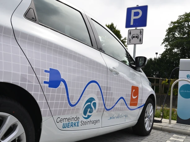 Mobilstation Steinhagen eAuto Ein Elektroauto der Gemeindewerke Steinhagen wird an einer Ladestation auf einem Parkplatz geladen.