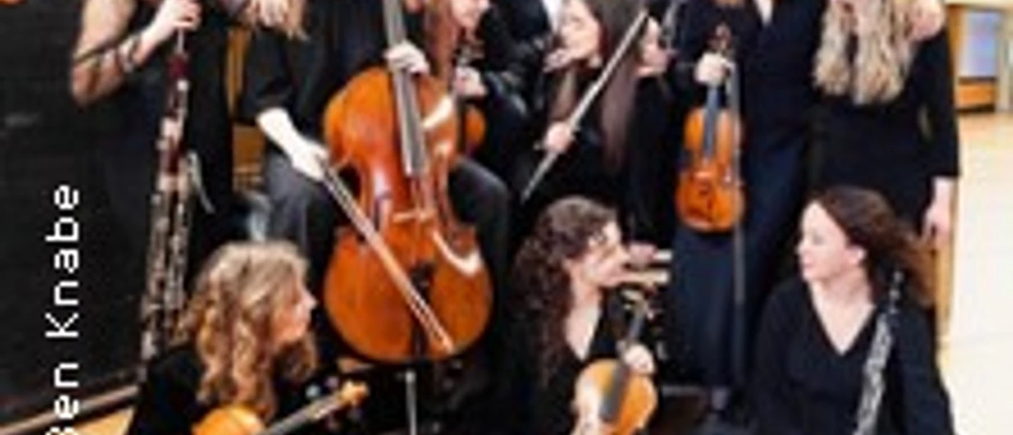 Gruppe junger Musikerinnen mit Streichinstrumenten in einem Saal während einer Probe