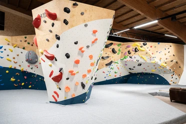 Boulderhalle-Garmisch-Partenkirchen Bunte Klettergriffe auf einer modernen Boulderwand in einer Halle.