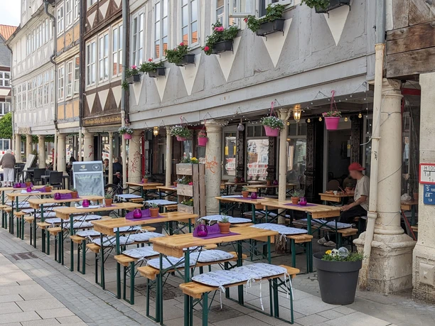 Bistro Provence Bierzelttische mit Sitzpolstern und liebevoller Deko vor Fachwerkhäusern
