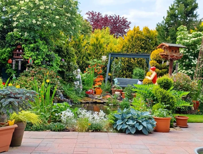 IMG-20240525-WA0016.jpg Ein liebevoll angelegter Garten mit üppiger Pflanzenpracht und einer einladenden Sitzbank am Teich.