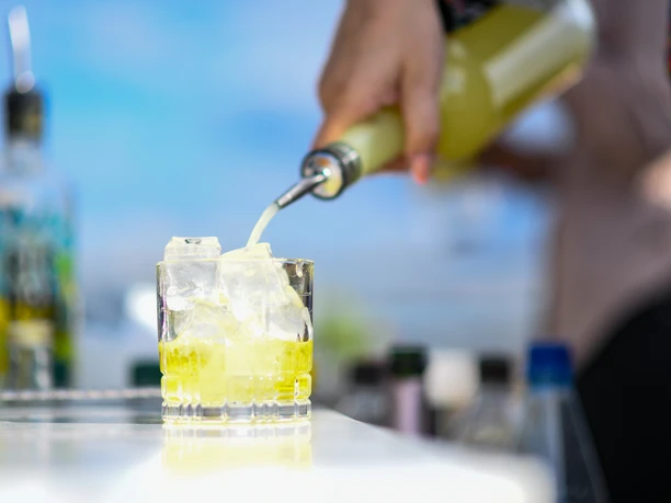 ESG_SummerStart2021_SZW_165.jpg Knallgelber Cocktail wird aus einer Flasche in ein Glas gegossen