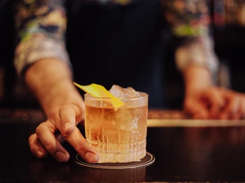 IMG_2551.jpg Eine Frau schiebt einen Cocktail über die ThekeA woman slides a cocktail over the bar