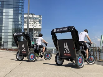 Rikolonia Citytour Rheinauhafen Zwei Rikschafahrer stehen in Rheinauhafen Köln
