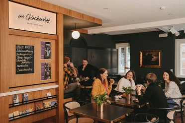 Café im Glockenhof Lachende Gäste unterhalten sich bei Kaffee im modernen Ambiente des Cafés im Glockenhof.