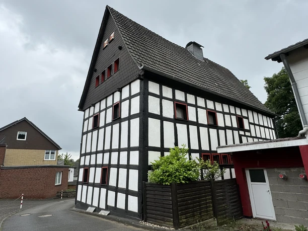 Haus Steeg Fachwerkhaus mit schwarz-weißer Fassade und rotem Rahmen, gelegen an einer ruhigen Straße.