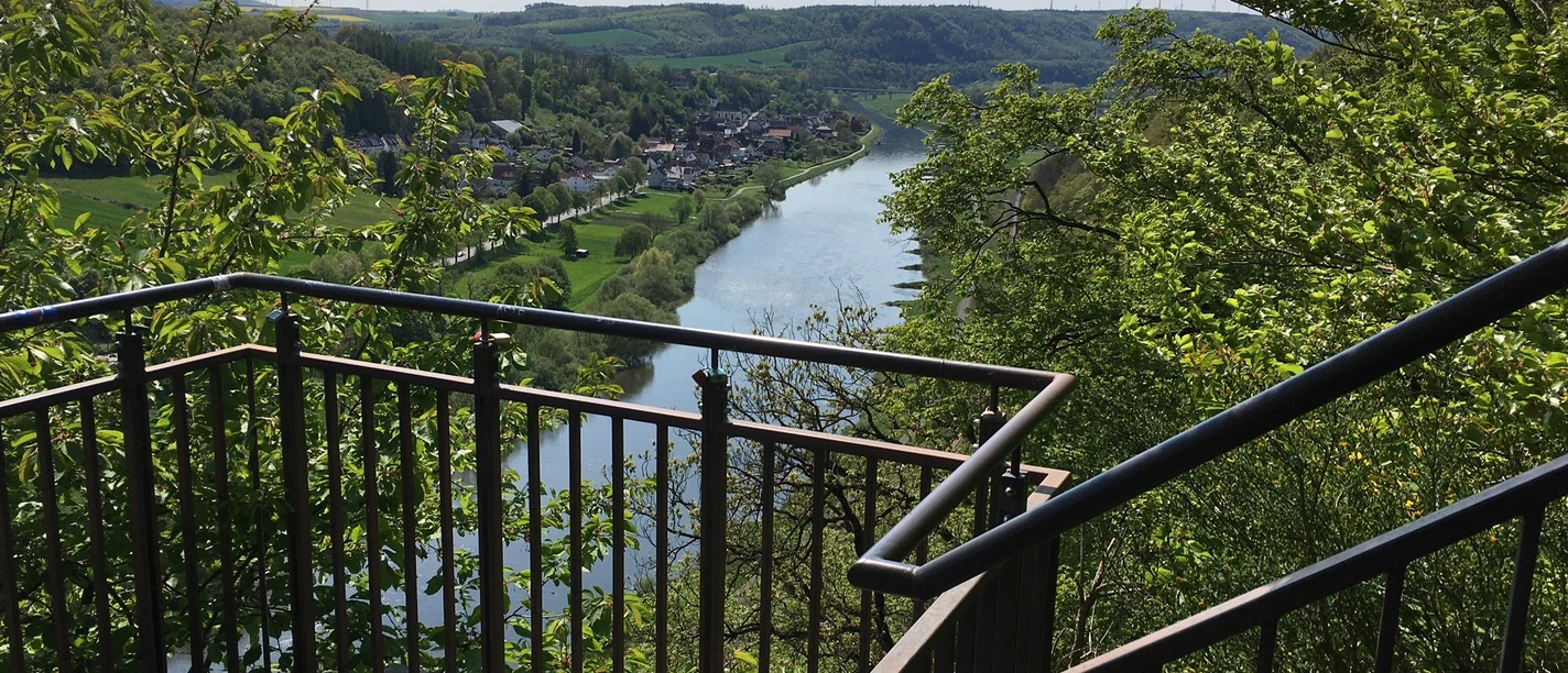 Weser-Skywalk Würgassen Aussichtsplattform mit Blick auf den Fluss Weser, umgeben von grünen Hügeln und üppigem Laub.
