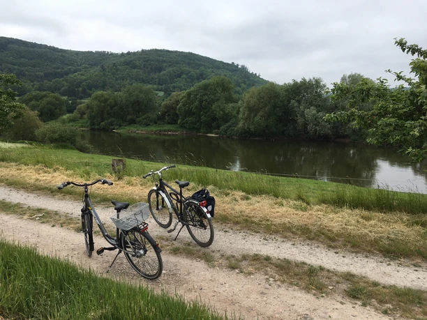 Radweg an der Weser bei Lauenförde Zwei Fahrräder stehen auf einem Kiesweg am Flussufer der Weser, umgeben von üppiger grüner Natur.