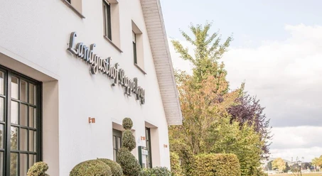 Landgasthof Pappelkrug Außenansicht eines weißen Gebäudes mit dem Schriftzug "Landgasthof Stempferhof" und gepflegten Büschen.