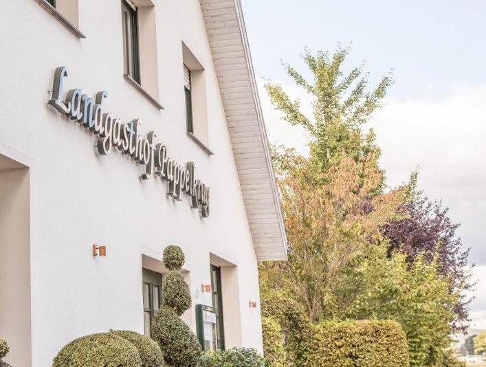 Landgasthof Pappelkrug Außenansicht eines weißen Gebäudes mit dem Schriftzug "Landgasthof Stempferhof" und gepflegten Büschen.
