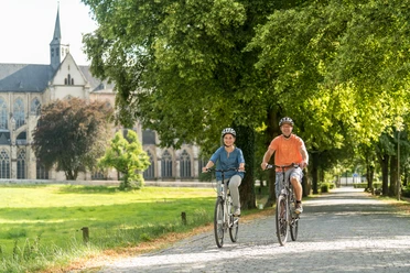Rad fahren in Altenberg Zwei Radfahrer fahren auf einem sonnigen Weg vor einer alten Kirche in einer grünen Landschaft.