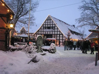 Verschneiter Weihnachtsmarkt am Wöhlehof Spelle mit Fachwerkhäusern, Lichterketten und Besuchern.