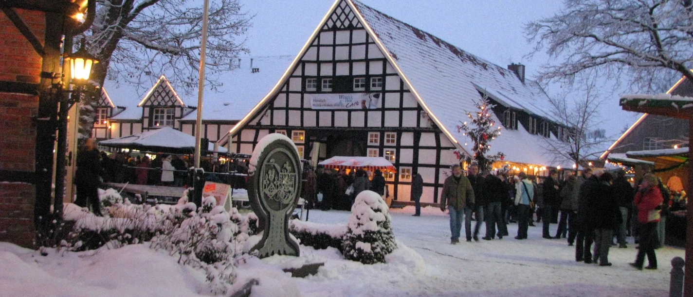 Wöhlehof Spelle Weihnachtsmarkt Verschneiter Weihnachtsmarkt am Wöhlehof Spelle mit Fachwerkhäusern, Lichterketten und Besuchern.