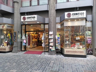 CONTIGO Aachen Eingang und Schaufenster des Geschäfts mit verschiedenen Produkten wie Taschen und Postkarten.