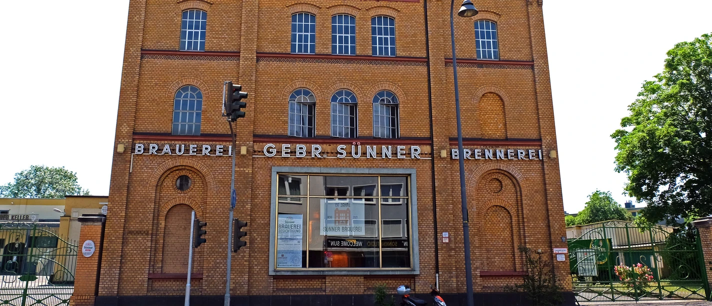 Brauwelt in Köln-Kalk Historisches Brauereigebäude in Köln-Kalk mit markanter Ziegelfassade und großen Fenstern bei blauem Himmel.