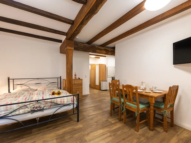 Gästezimmer "Sonnenblume" im Hof Karpenhaus in Ratingen Gästezimmer mit Holzbalken, Doppelbett und Esstisch, warm eingerichtet und komfortabel ausgestattet.