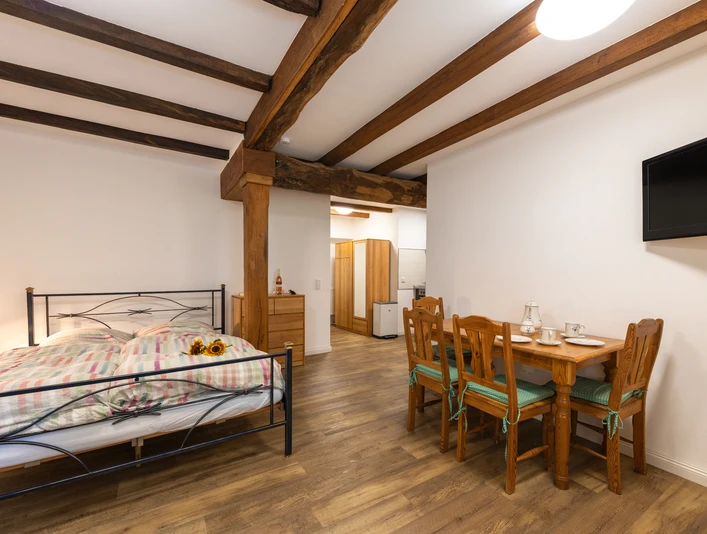 Gästezimmer "Sonnenblume" im Hof Karpenhaus in Ratingen Gästezimmer mit Holzbalken, Doppelbett und Esstisch, warm eingerichtet und komfortabel ausgestattet.
