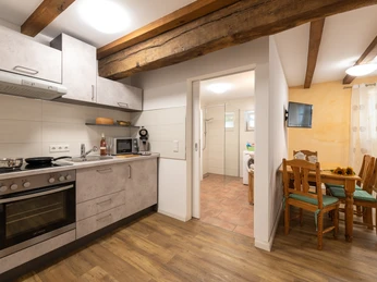 Gästezimmer "Sonnenblume" im Hof Karpenhaus in Ratingen Eine moderne, voll ausgestattete Küchenzeile und ein Essbereich mit warmem Holztisch und Stühlen.