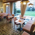 Hotel-Pension Bevertal Garni - Frühstücksraum Frühstücksraum mit Tischgruppen, gepolsterten Stühlen und Sitzbänken, Blick in den grünen Garten, an der Wand ein Holzbuffet und Bilder
