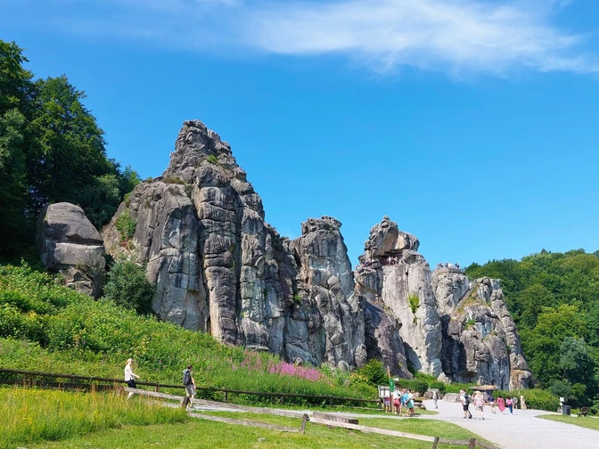 Sandsteinfelsen in Norddeutschland, bekannt als Externsteine, umgeben von Wald und Grünflächen.