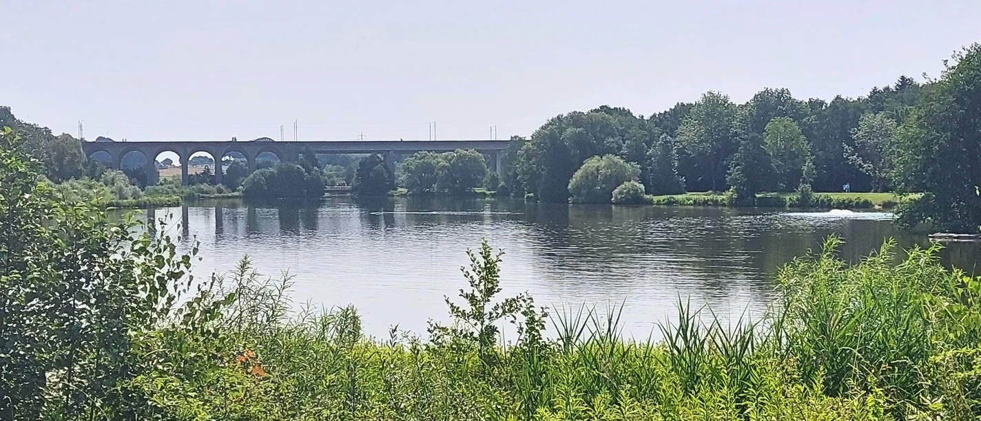 Obersee_CC_BY_SA_BadSalzuflen_KerstinPaar.jpg Ein Viadukt überspannt einen ruhigen See mit umgebender Bewaldung und dichter Vegetation.
