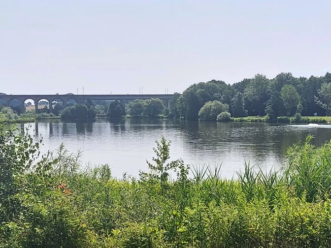 Obersee_CC_BY_SA_BadSalzuflen_KerstinPaar.jpg Ein Viadukt überspannt einen ruhigen See mit umgebender Bewaldung und dichter Vegetation.