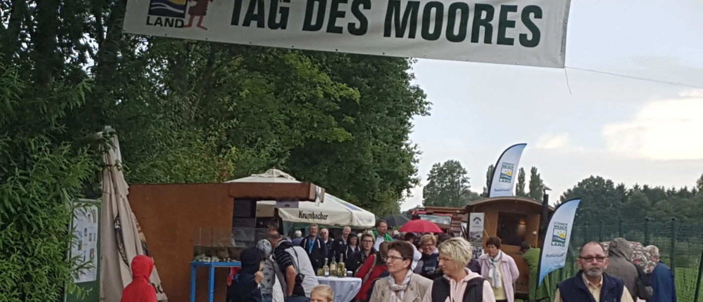 Besucherinnen und Besucher unter einem Banner beim Tag des Moores in Essern.