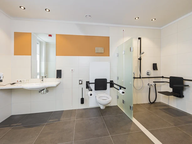 Badezimmer im Hotel Neues Pastorat Helles barrierefreies Hotelbadezimmer mit moderner Ausstattung, Haltegriffen und bodengleicher Dusche.