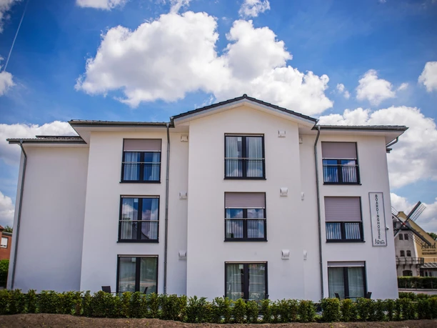 Boardinghouse am Teuto Lengerich Ein modernes Boardinghouse mit weißer Fassade und mehreren Fenstern unter einem blauen Himmel.