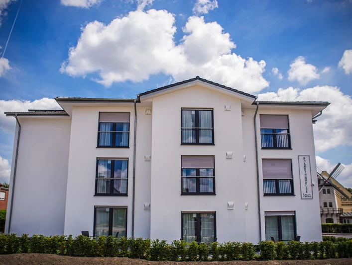 Boardinghouse am Teuto Lengerich Ein modernes Boardinghouse mit weißer Fassade und mehreren Fenstern unter einem blauen Himmel.