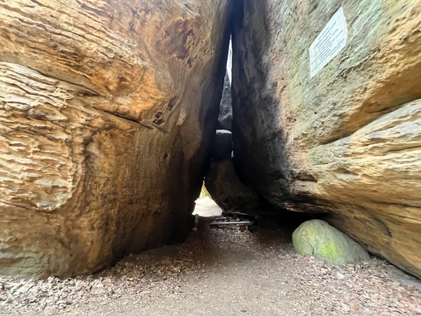 Götzinger Höhle Schmale Felsformation mit sandfarbenen, strukturierten Wänden und einem kleinen Durchgang; ein Schild ist an der rechten Wand angebracht.