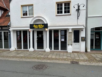 Das Restaurant Hani’s Kitchen präsentiert eine weiße Fassade mit großen Fenstern und einem gelben Logo.