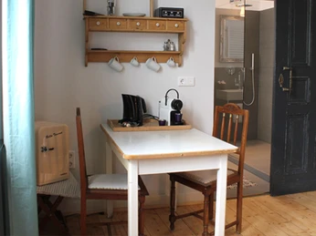 Küchentisch in der Fabrikantenvilla in Erkrath Ein kleiner Küchentisch mit zwei Stühlen steht vor einem Regal mit Tassen und Retro-Radio.