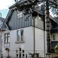 Fabrikantenvilla in Erkrath Eine prächtige Villa mit historischer Fassade und modernen Akzenten, umgeben von Bäumen und Zäunen.