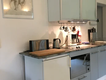 Küche in der Gästewohnung Kleiner Bollenhof Moderne Küche mit hellen Schränken, Kaffeemaschine, Wasserkocher und Toaster auf der Arbeitsplatte.