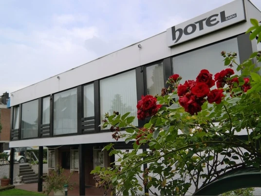 Hotel am Hallenbad Moderne Fassade des Hotels am Hallenbad mit leuchtenden roten Rosen im Vordergrund.
