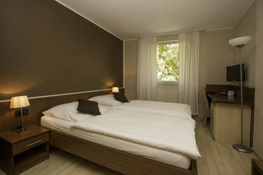 Zimmer in Hotel und Restaurant Haus Fabry in Hilden Modern eingerichtetes Hotelzimmer mit Doppelbett, Schreibtisch, Flachbildfernseher und warmem Licht.