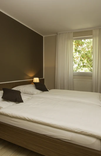 Zimmer in Hotel und Restaurant Haus Fabry in Hilden Modern eingerichtetes Hotelzimmer mit Doppelbett, Schreibtisch, Flachbildfernseher und warmem Licht.