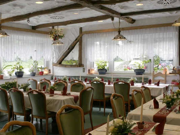 Gastraum im Hotel und Restaurant Haaner Hof in Haan Gemütlicher Gastraum mit rustikalem Holzgebälk, gedeckten Tischen und großen Fenstern mit Blumenschmuck.
