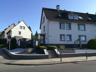 Dreigeschossiges Wohngebäude mit weißer Fassade und Schieferdach in einer ruhigen Wohngegend.