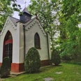 Bredemeiers Kapelle in Hövelhof, umgeben von Bäumen, mit spitzem Dach und dekorativen Fenstern.