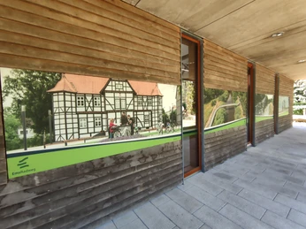 Fachwerkfassade im Ems-Infozentrum mit Radfahrern auf dem EmsRadweg in Hövelhof, modern gestaltet.