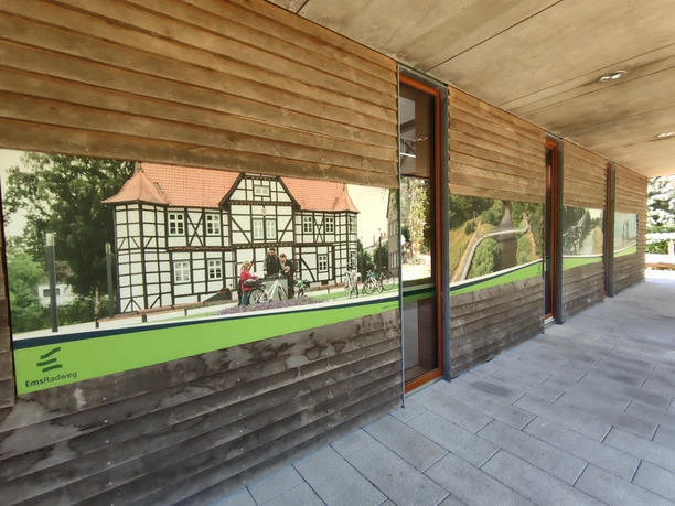 Fachwerkfassade im Ems-Infozentrum mit Radfahrern auf dem EmsRadweg in Hövelhof, modern gestaltet.