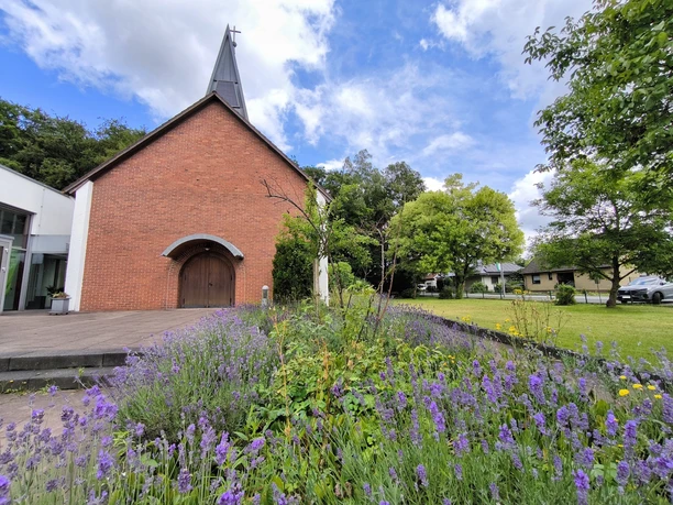 Evangelische Johanneskirche Hövelhof aus rotem Ziegel mit einem Stufengiebel und modernem Anbau.
