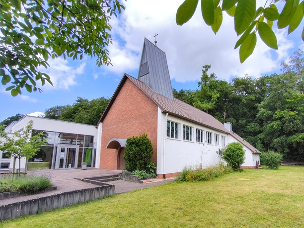 Evangelische Johanneskirche Hövelhof Die evangelische Johanneskirche in Hövelhof vereint moderne und traditionelle Architektur umgeben von Grün.