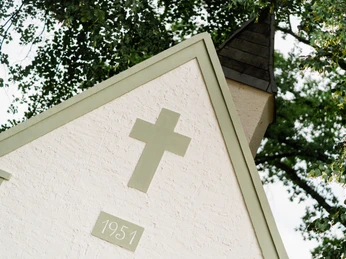 Neogotische Kapelle von 1951, mit grünem Kreuz verziert, von Bäumen umrahmt in Hövelhof-Espeln.