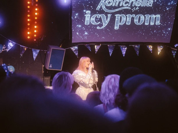 Koelnchella_Icy-Prom22.jpg Sängerin auf Bühne vor Publikum bei einem festlich beleuchteten Event