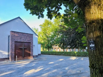 Friedhofskapelle Hövelhof Friedhofskapelle in Hövelhof aus Backstein und Putz, umgeben von grünen Bäumen und schattigem Bereich.