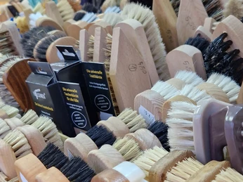 Eine Nahaufnahme handgefertigter Bürsten in verschiedenen Formen und Farben auf einem Marktstand.